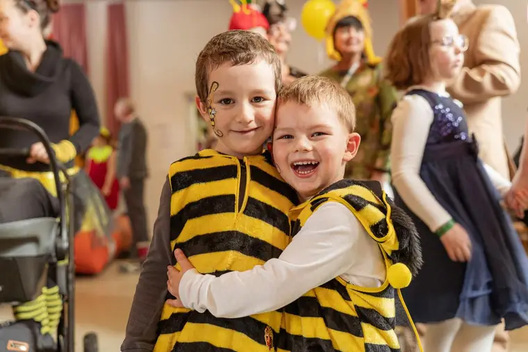 Zwei Kinder in Bienenkostümen lachen in die Kamera