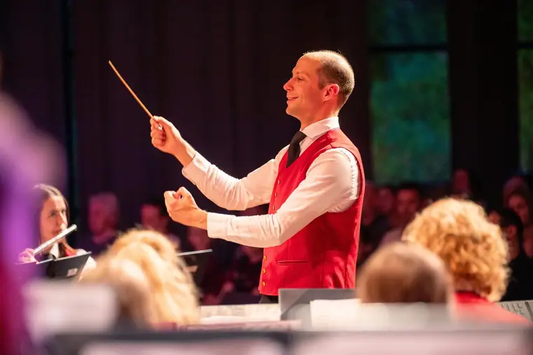 Dirigent mit erhobenem Taktstock vor seinem Orchester