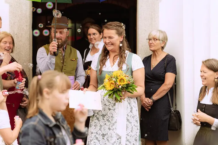 Brautpaar in Tracht kommt aus der Kirche, Gäste mit Seifenblasen
