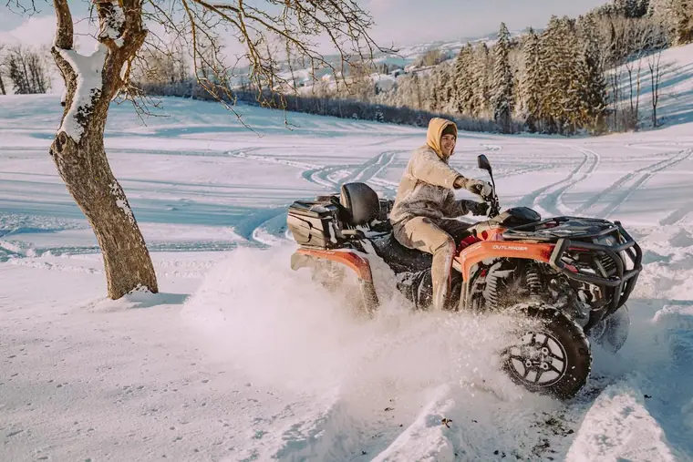 Junger Mann fährt mit einem Quad durch den Schnee