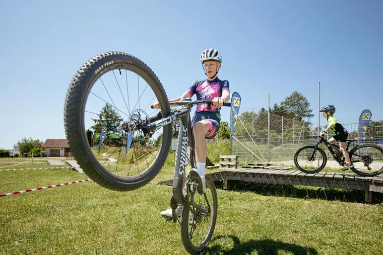 Junger Radfahrer stellt sein Mountainbike auf dem Hinterrad auf