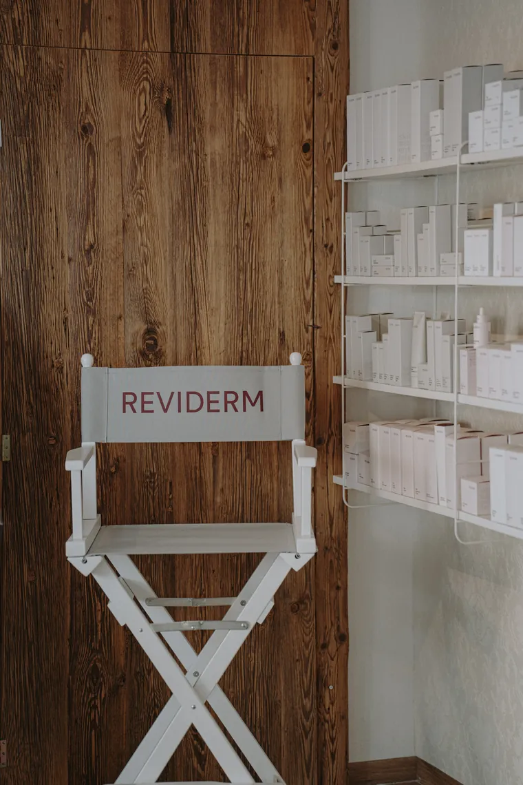 Weißer Regiestuhl mit REVIDERM-Schriftzug vor einer alten Holztür